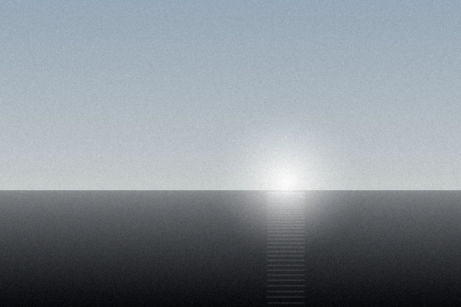 Pale sky and bright sun over flat grey land